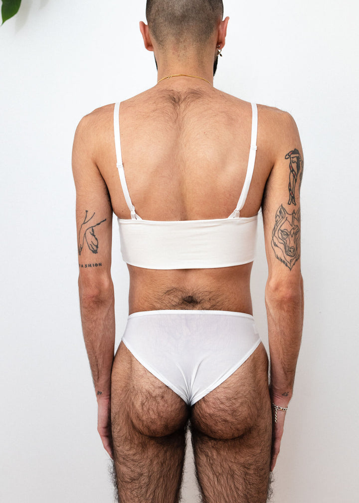 ENBY person wearing a white tucking underwear compression gaff with a cheeky cut, Detail photographed from the back.