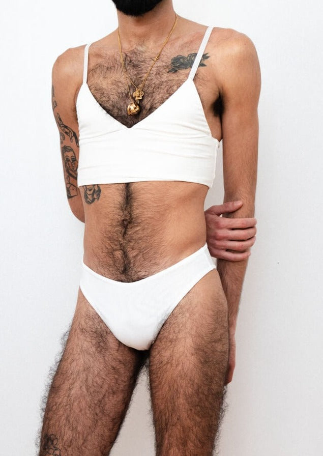 ENBY person wearing a white tucking underwear compression gaff with a cheeky cut. Detail photographed from the front.