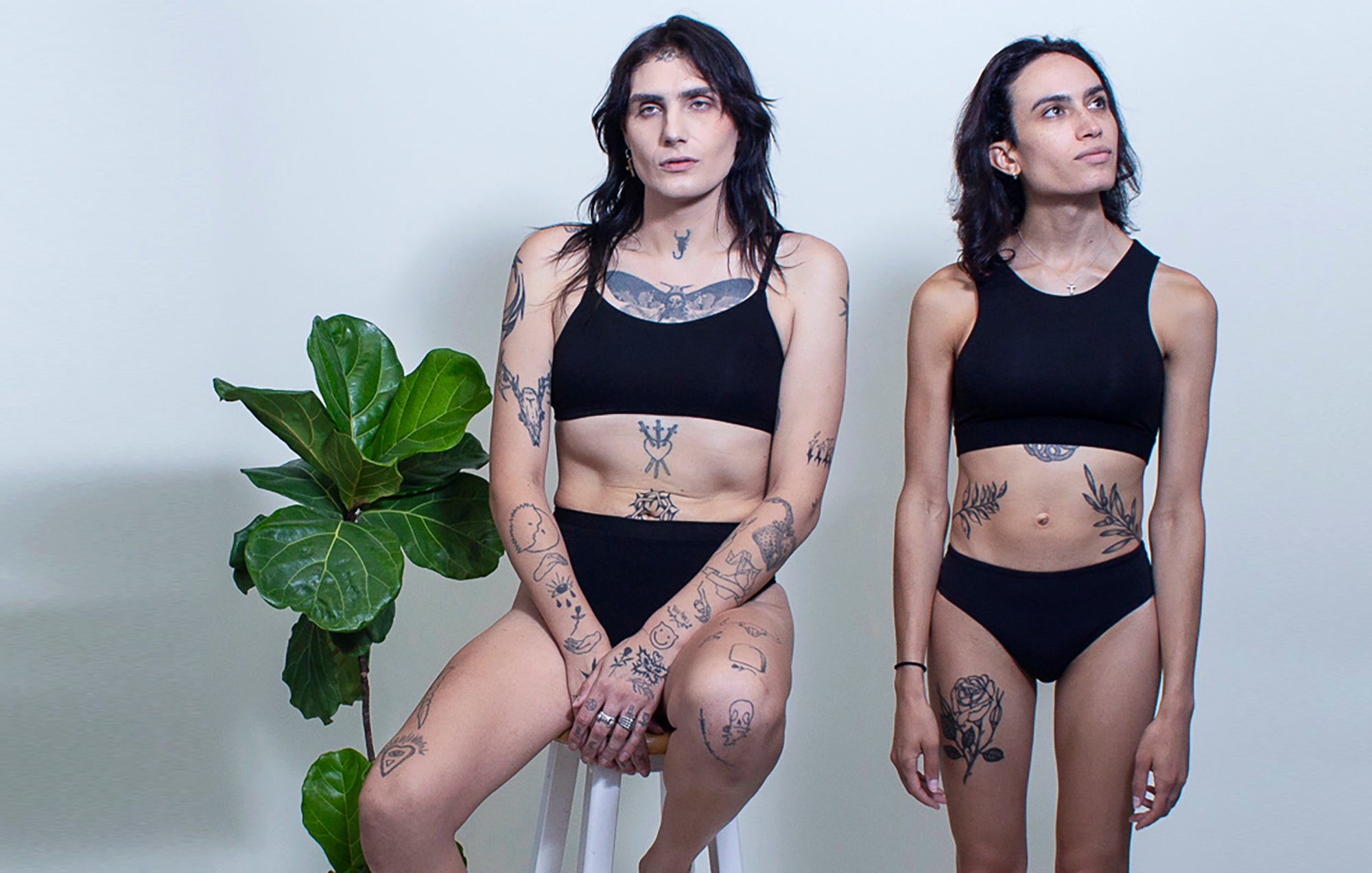 Two lingerie models wear gender-affirming custom lingerie. The plus size model wears a Plus size bra and panty sets and the other model wears a sustainable bamboo lingerie set. 