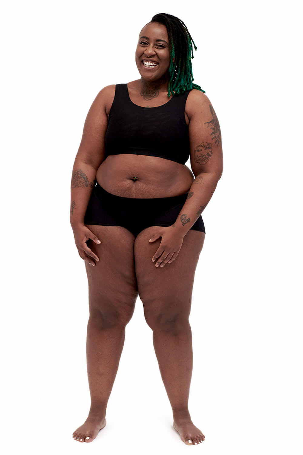 Plus-sized person wearing a black sports bra style chest binder made from breathable mesh, photographed from the front.