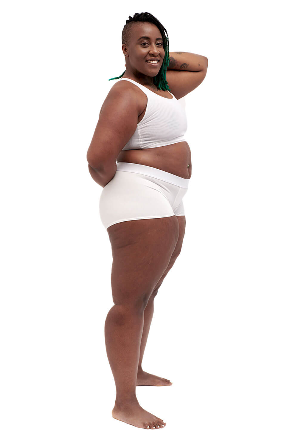 Plus-sized person wearing a white racerback chest binder made from breathable mesh, photographed from the side.