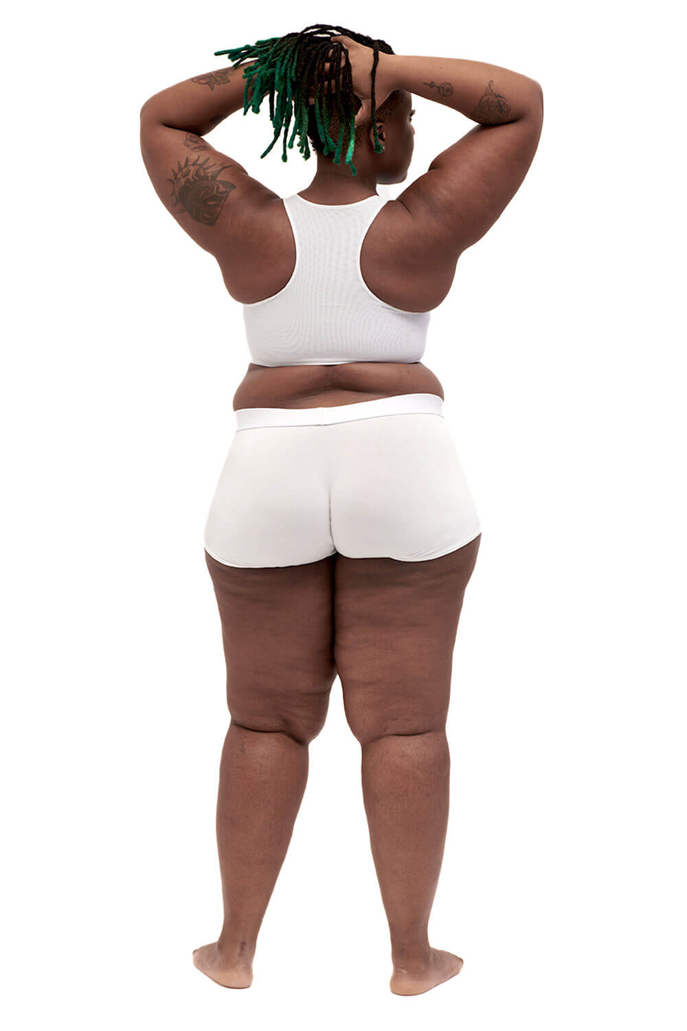 Plus-sized person wearing a white racerback chest binder made from breathable mesh, photographed from the back.