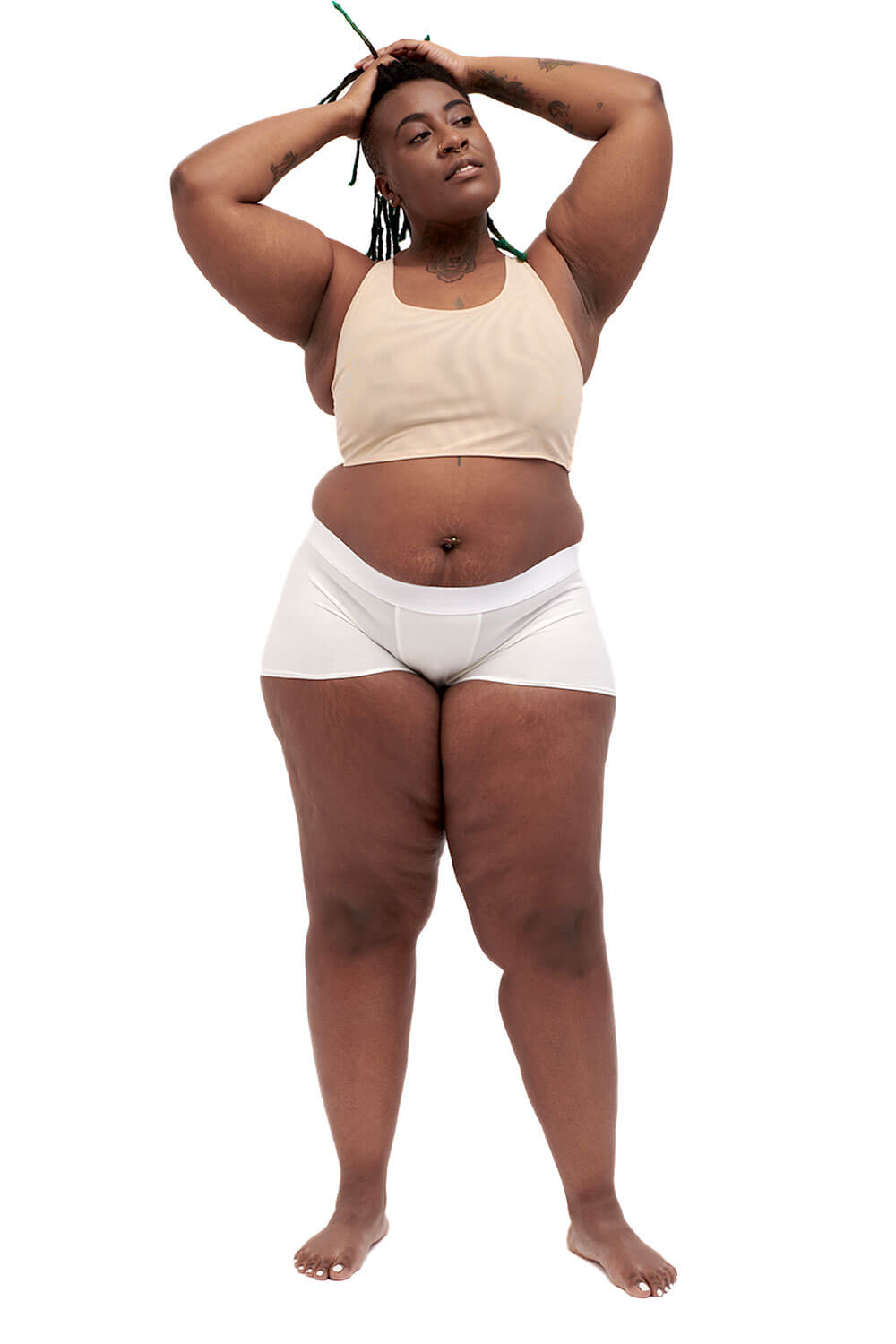 Plus-sized person wearing a nude racerback side-open chest binder made from breathable mesh, photographed from the front with arms up.