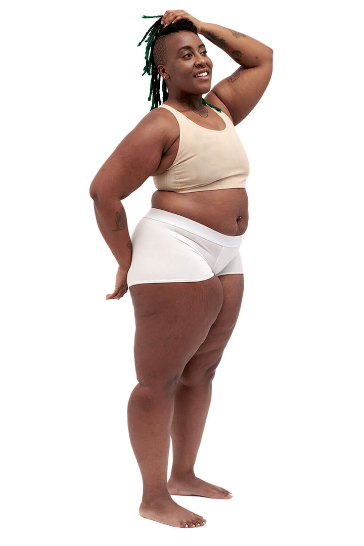 Plus-sized person wearing a nude racerback side-open chest binder made from breathable mesh, photographed from the side.