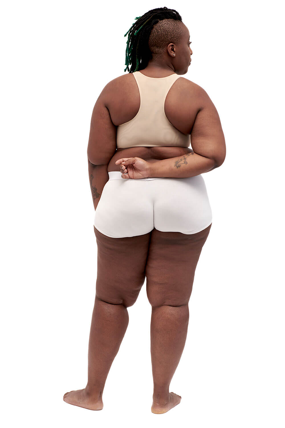 Plus-sized person wearing a nude racerback side-open chest binder made from breathable mesh, photographed from the back.