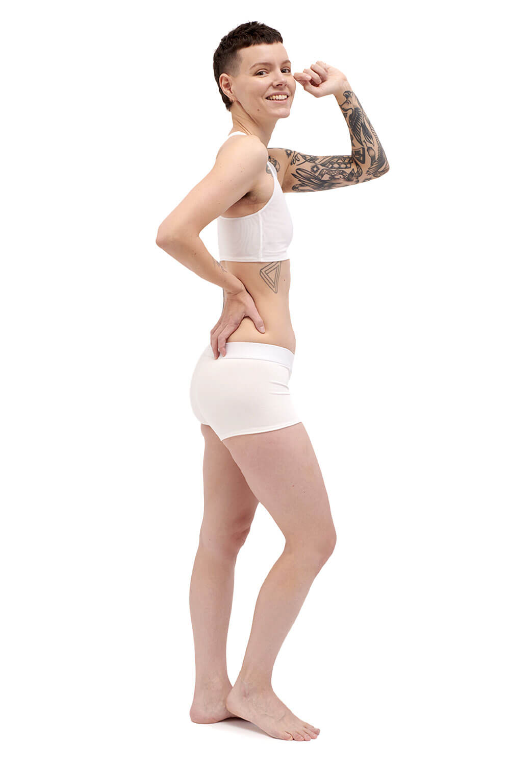 Petite person wearing a white racerback side-open chest binder made from breathable mesh, photographed from the left side.