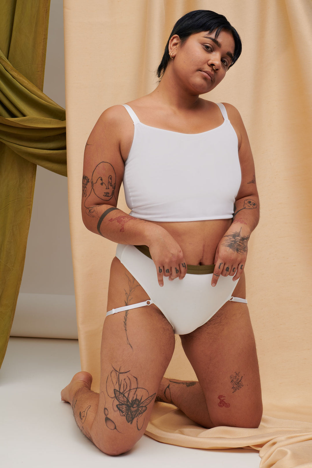 A Transgender Non-binary model look at the camera in the ortie sustainable collection mesh compression binder and ethical bamboo underwear. They look confident in their gender affirming chest binder