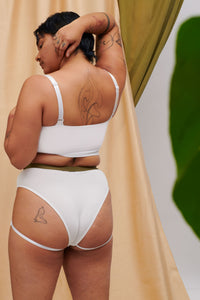 A Transgender Non-binary model in the ortie sustainable collection mesh compression binder and ethical bamboo underwear. We see the back of the gender affirming chest binder and cheeky undies