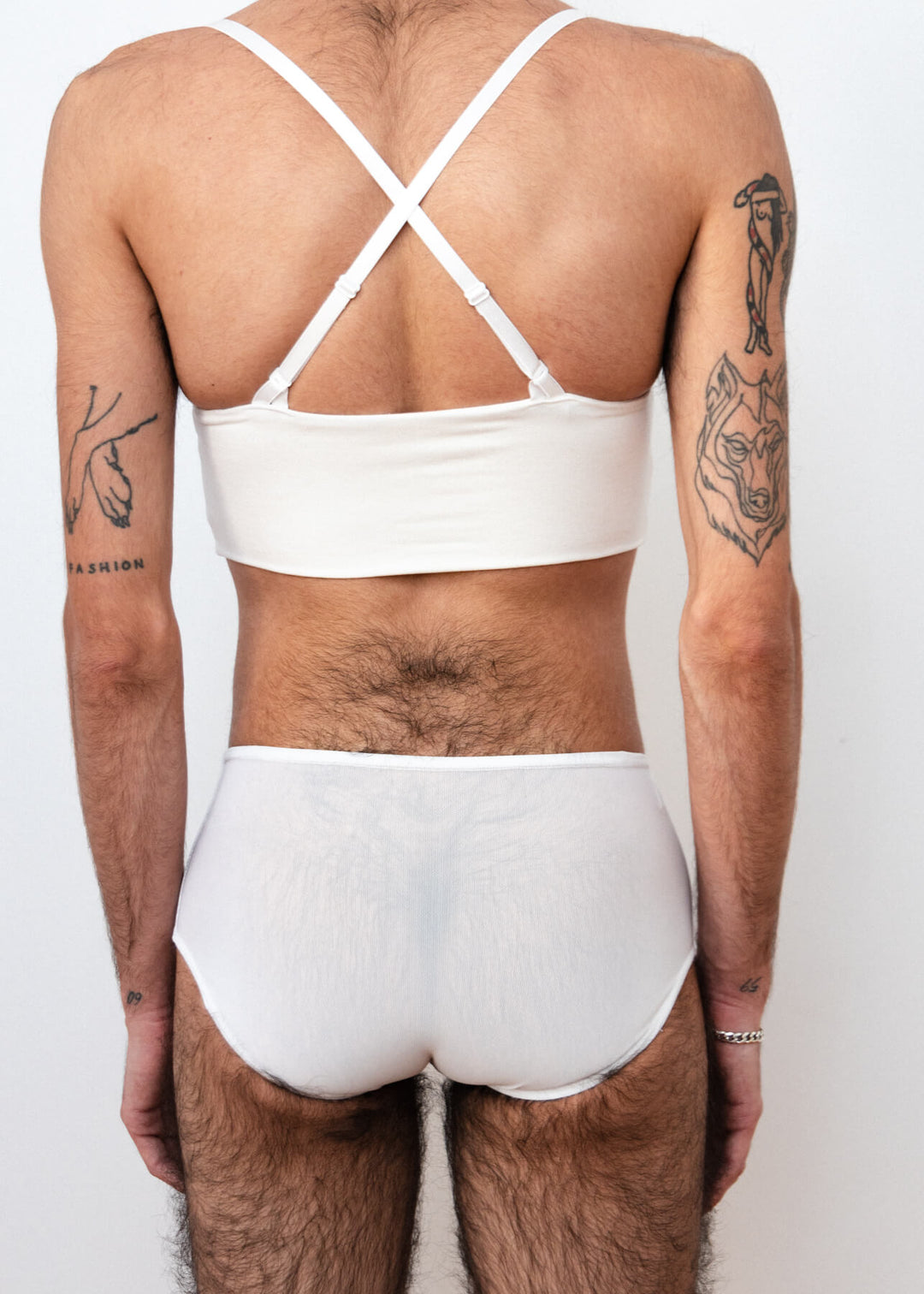 Detail of a mtf transgender white compression gaff with a boyshort cut and a white bamboo bra, photographed from the back.
