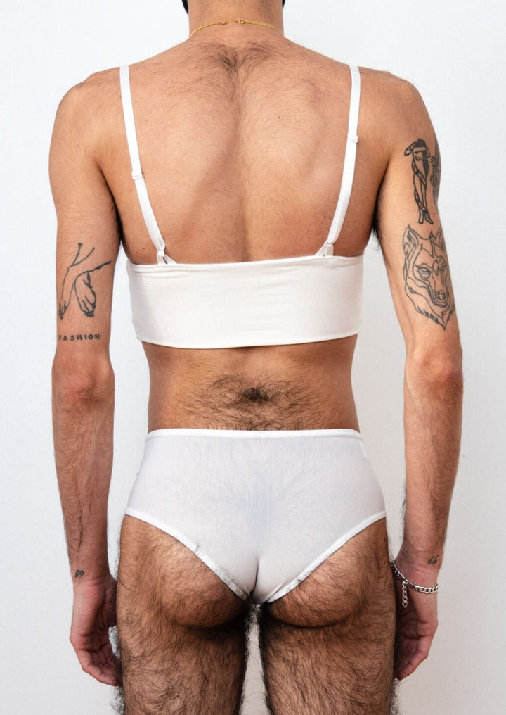 Detail of a mtf transgender white compression gaff with a ckeey boyshort cut and a white bamboo bra, photographed from the back. 
